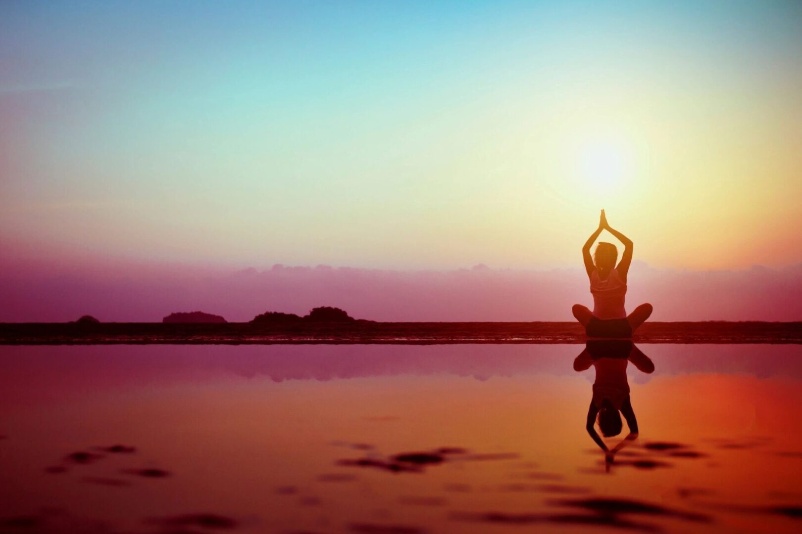 A person doing yoga on the beach at sunset